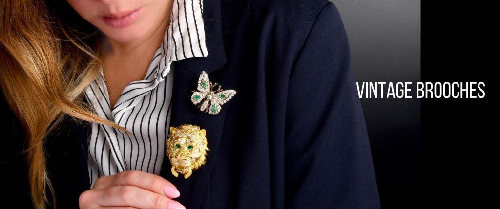 Vintage brooches from Dover Jewelry, featuring a lion and butterfly design with emerald and diamond accents, showcasing exquisite craftsmanship and timeless style